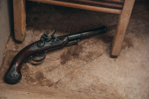 Colonial flintlock laying under wooden chair.
