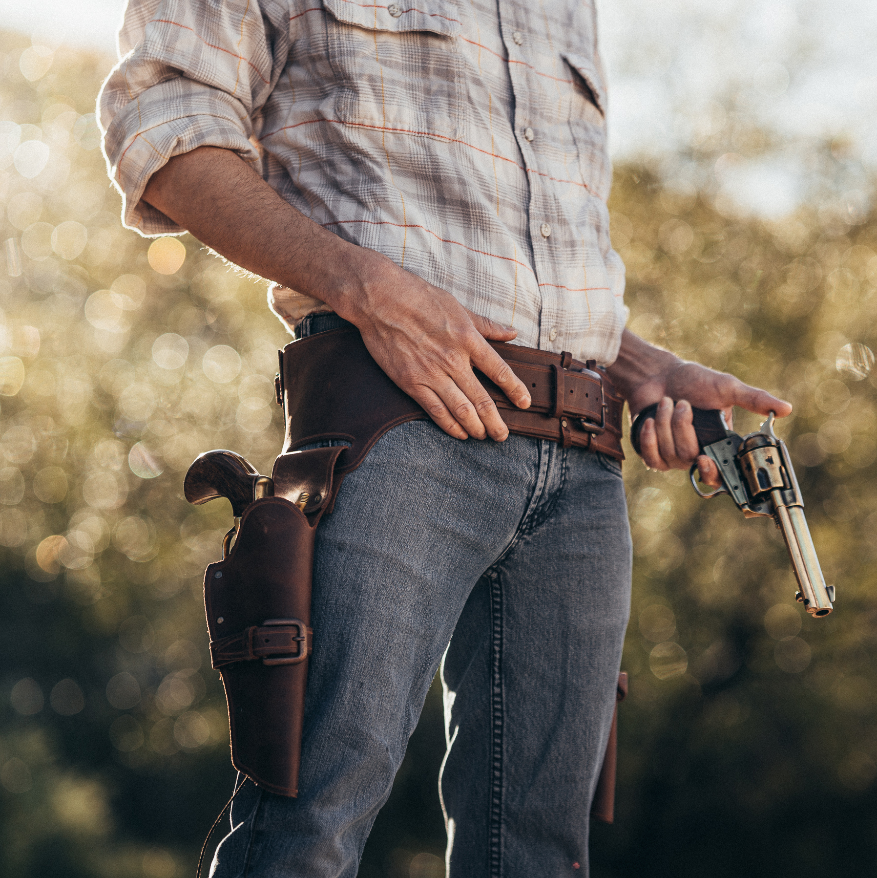 Bottom half of Cowboy wearing Winchester style bandolier holding Thunderer revolver.