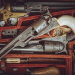 A collection of vintage revolvers displayed in a red velvet-lined case