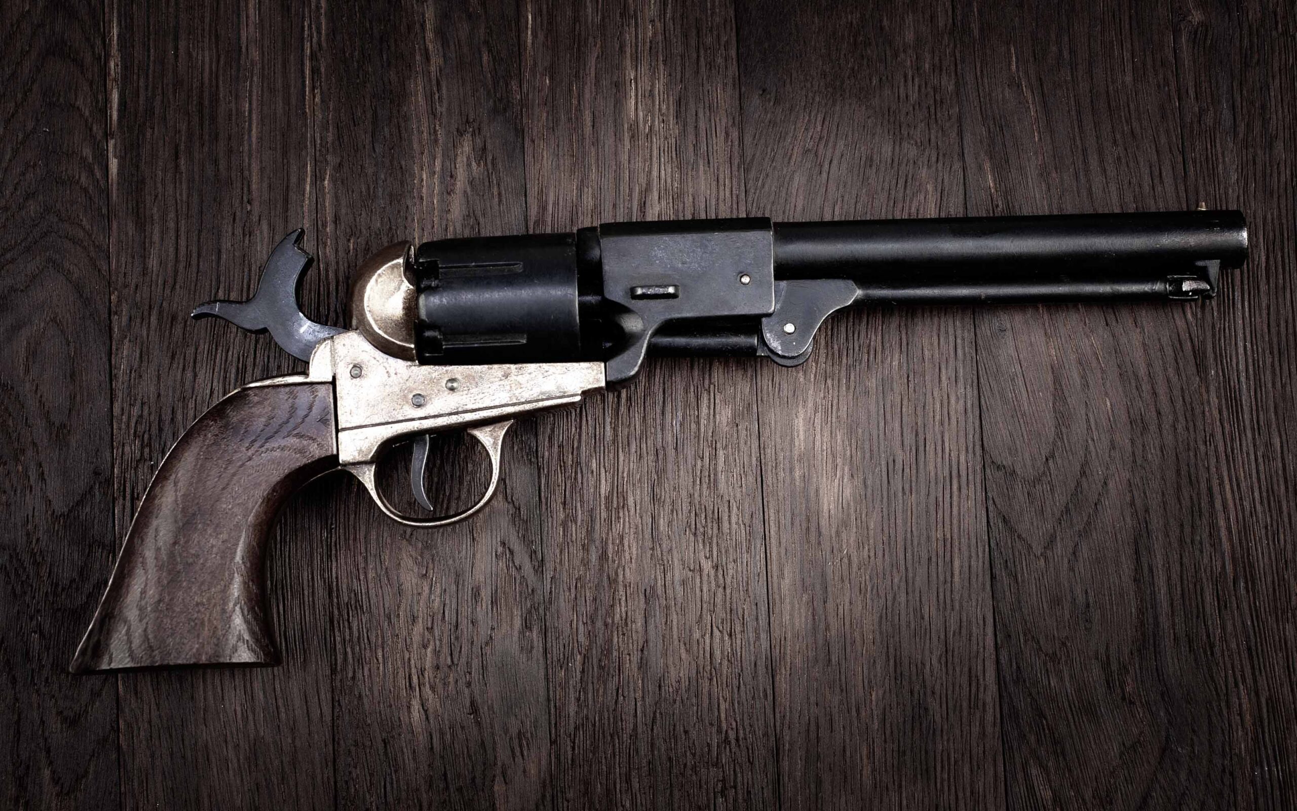 Vintage revolver with wooden grip and long barrel on a dark wooden surface